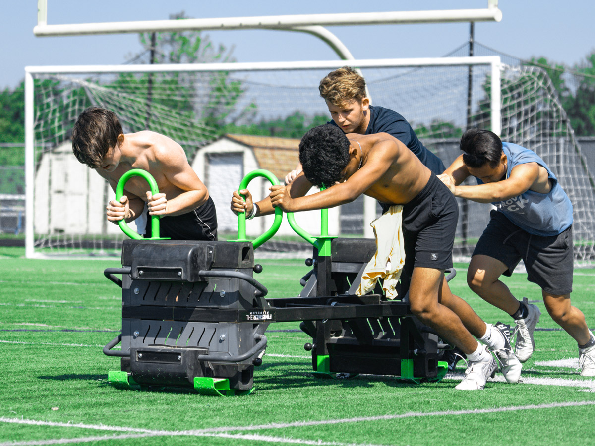 Four Football Players Pushing Team Sled